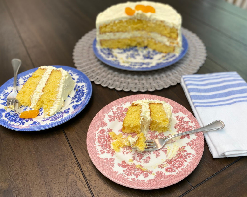 A slice of cake with a fork, and a sliced cake in the background. [pea picking cake]
